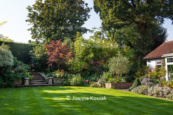 Stone stairs amongst flowerbeds in Autumn leading to hidden path of the higher level of the garden.