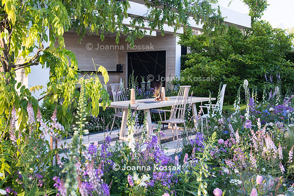 Patio with wooden chairs, table and made from Accoya (design by Nils Verweij) amongst pink and white spring flowers: Persicaria bistorta 'Superba', Hesperis matronalis, Rosa 'Natasha Richardson', Digi