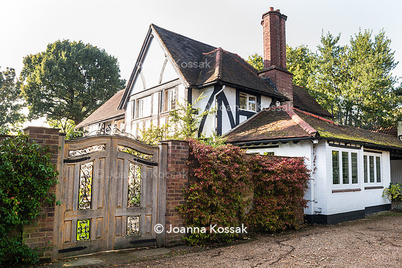View of the house and wooden gate leading to the garden with Trachelospermum jasminoides (Confederate jasmine) covering the wall